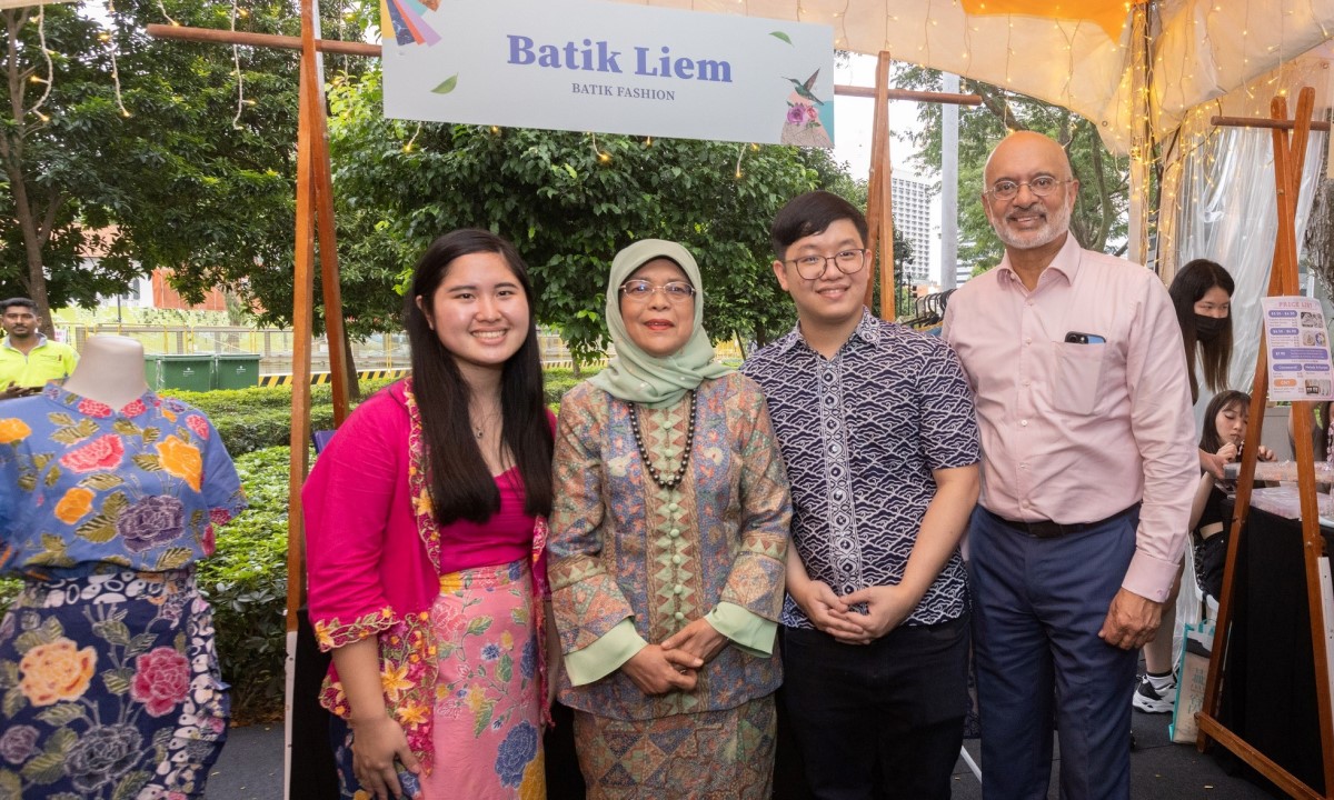 President Halimah and SMU Board of Trustees Chairman, Mr Piyush Gupta, with the student makers of Batik Liem.