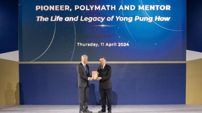 Justice Andrew Phang presenting the newly launched book to Prime Minister Lee Hsien Loong.